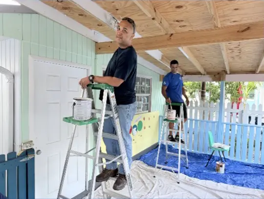 Volunteers painting overhead beams.